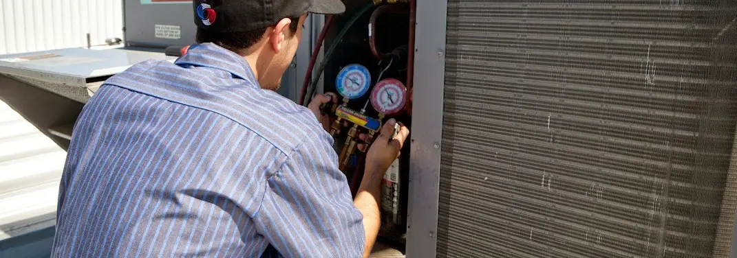 HVAC technician servicing a condenser unit in Escalon